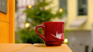 A steaming mug of Glühwein against a backdrop of a German Christmas market