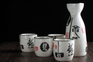 A traditional Japanese setting with a steaming flask of Sake and small ceramic cups